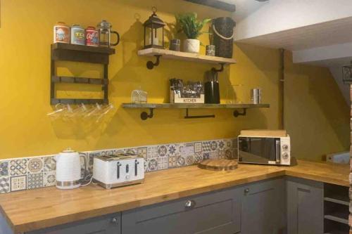 a kitchen with yellow walls and a counter with a microwave at 3 bedroom cottage with hot tub and stunning views in Conwy