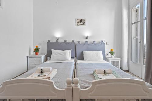 a white bedroom with two beds and two windows at Unforgettable Return To Timeless Spetses in Spetses