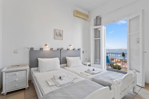 a bedroom with two beds and a large window at Unforgettable Return To Timeless Spetses in Spetses