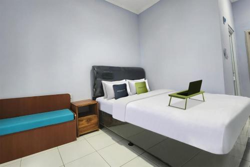 a hotel room with two beds and a chair at Urbanview Hotel Mutiara Persada Syariah Majalengka by RedDoorz 