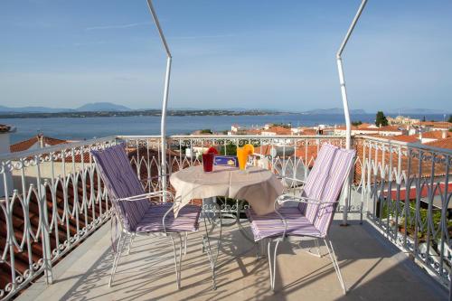 a table and chairs on a balcony with a view of the water at Unforgettable Return To Timeless Spetses in Spetses