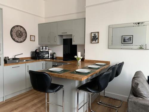 a kitchen with a wooden counter top and black chairs at Market Place Serviced Apartments, Leek in Leek