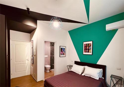 Un dormitorio con una pared de acento verde y una cama en The B Place Cola, en Roma