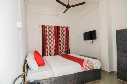 a bedroom with a bed with red pillows and a ceiling fan at Jp Homes in Kamakhya