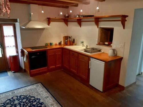 une cuisine avec des armoires en bois, un évier et une cuisinière dans l'établissement Wisteria Cottage, à Les Adjots
