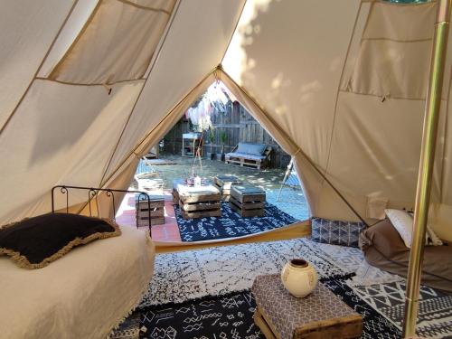 une tente avec un lit et une table. dans l'établissement Le Bivouac, à Cabariot