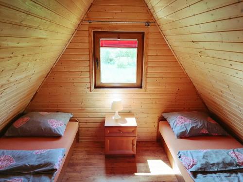 two beds in a log cabin with a window at Domki Letniskowe - Leśne Zacisze in Jarosławiec