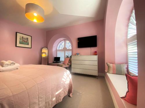 a bedroom with pink walls and a bed and a tv at Sublime waterfront retreat with private terrace in Bristol