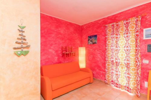 um sofá laranja num quarto com paredes cor-de-rosa em Casa Maria 250m From The Beach - Happy Rentals em Porto Pozzo