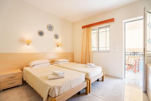 two beds in a room with a window at Olympus Tilos Apt Twin B1 in Livadia