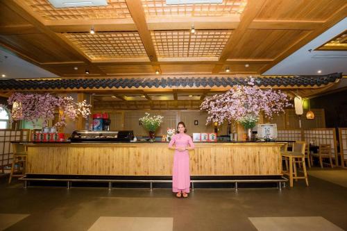 a woman in a pink dress standing in front of a bar at Hai Phong Tower - Apartment & Hotel in Hai Phong