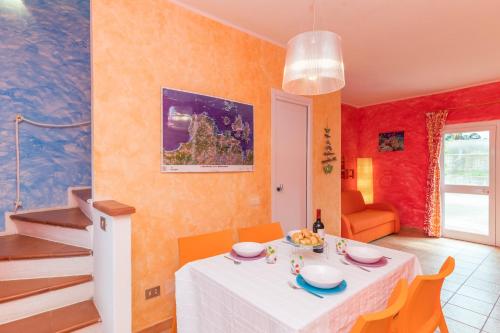 un comedor con una mesa blanca y paredes de color naranja en Casa Maria 250m From The Beach - Happy Rentals en Porto Pozzo