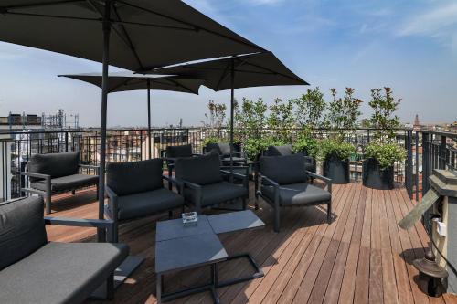 un patio con sedie, tavoli e ombrelloni sul tetto di PRESTIGE BOUTIQUE APARTHOTEL - Piazza Duomo View a Milano