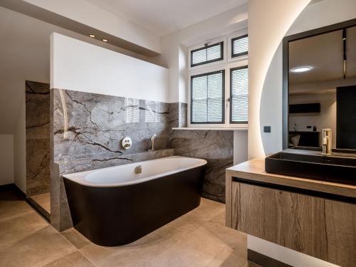a bathroom with a large tub and a sink at Lindenhuys Logies in Sint-Oedenrode