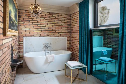 a bathroom with a white tub and a brick wall at Mystery Hotel Budapest, Preferred Hotels & Resorts in Budapest