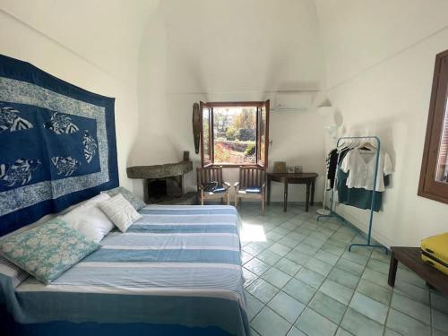 a bedroom with a bed and a table and a window at Casa Nocilla, un dammuso sul mare! in Pantelleria