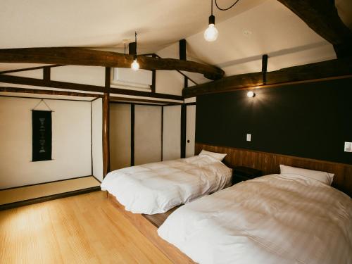 2 camas en una habitación con suelo de madera en 龍野城下町古民家ホテル kurasu en Tatsuno