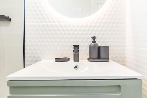a bathroom sink with a bottle and a mirror at Le Shopper - Confortable et Lumineux - Parking in La Chapelle-Saint-Luc