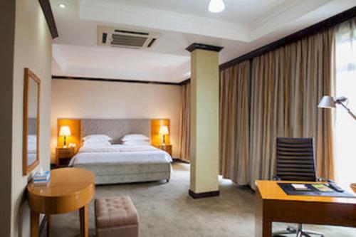 Habitación de hotel con cama y escritorio en Gorillas Golf Hotel, en Kigali