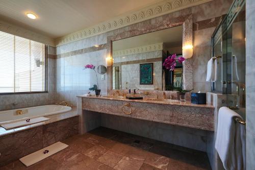 uma casa de banho com uma banheira e um espelho grande em The Empire Brunei em Bandar Seri Begawan