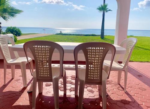 a table and chairs on a porch with a view of the ocean at Villa avec jardin sur la plage - Complexe Al Amine in Fnidek