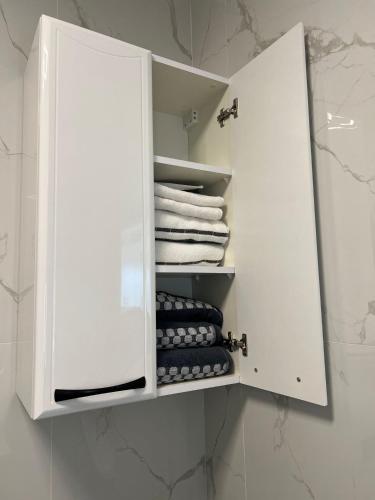 biała szafka z ręcznikami i ręcznikami w łazience w obiekcie Krasta Home apartament Free Parking With CITY & RIVER VIEW w Rydze