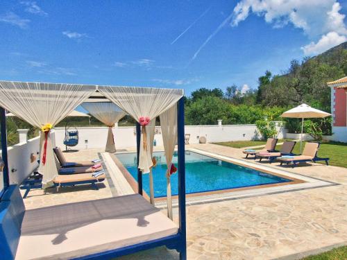 a backyard with a pool with chairs and a bed and umbrella at Angelloti Exclusive Beach Villa in Ágios Matthaíos