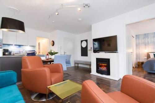 a living room with orange chairs and a fireplace at Duenenresidenz Heringsdorf App 01 in Bansin