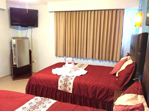 ein Hotelzimmer mit zwei Betten und einem Flachbildfernseher in der Unterkunft Hotel Isleño in Isla Mujeres