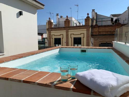 a swimming pool with two glasses on the edge of a house at La Casa del Pintor Apartments in Seville