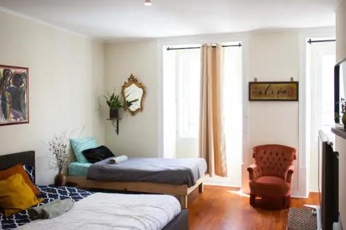 a bedroom with two beds and a chair and a window at Boho Chic Apt in Vila Franca de Xira