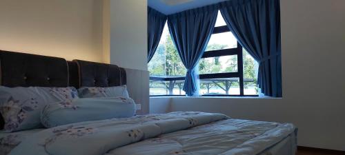 a bedroom with a bed with blue curtains and a window at Sunsky Condominium Homestay 2 in Miri