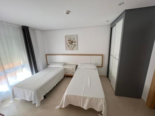 2 camas en una habitación con ventana en Apartamentos Flamingo Hills, en Benitachell