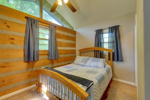 a bedroom with a crib and a wooden wall at Porch and Fire Pit Family-Friendly Afton Cabin! in Greeneville