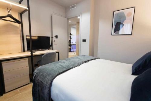 Schlafzimmer mit einem Bett, einem Schreibtisch und einem TV in der Unterkunft Apartamento Milano Living Suites en Vila real in Villareal