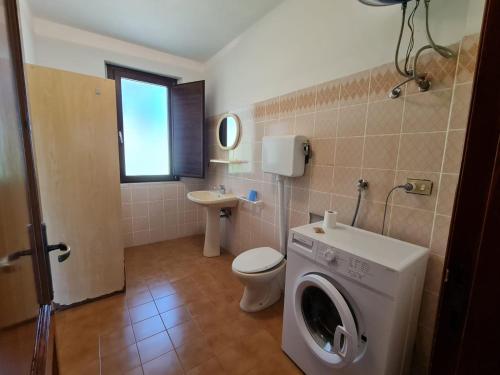 a bathroom with a washing machine and a toilet at VILLA TO' in Àrbatax