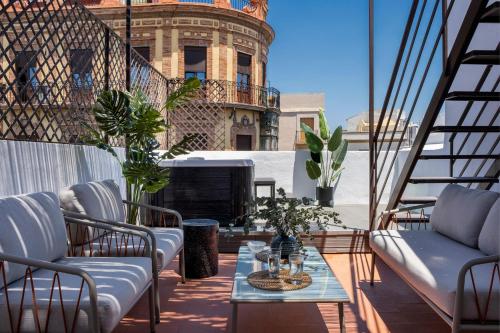 balcón con sillas, mesa y chimenea en Suites Maestranza - Puerta del Arenal by Magno Apartments, en Sevilla