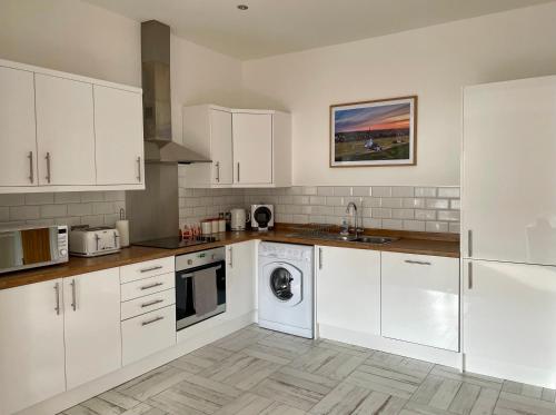 cocina con armarios blancos y lavavajillas en Apartment 33 Lytham en Lytham St Annes