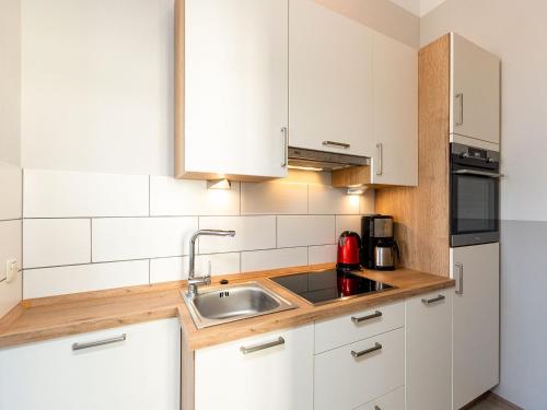 eine Küche mit weißen Schränken und einem Waschbecken in der Unterkunft Villa Amelia, App. 06 in Heringsdorf