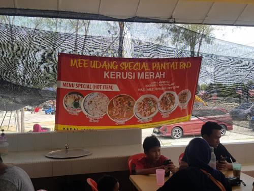 a group of people sitting at a restaurant with a sign at As Sufi Villa in Kampung Sungai Air Tawar
