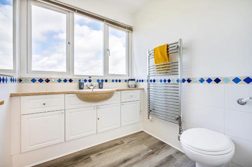 a bathroom with a toilet and a sink at Family Beachfront Bliss Sleeps 10 in Pevensey
