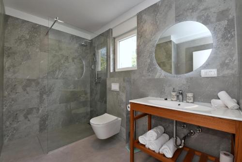 een badkamer met een wastafel, een toilet en een spiegel bij Villa Sophia with private swimming pool near the beach! in Zakučac