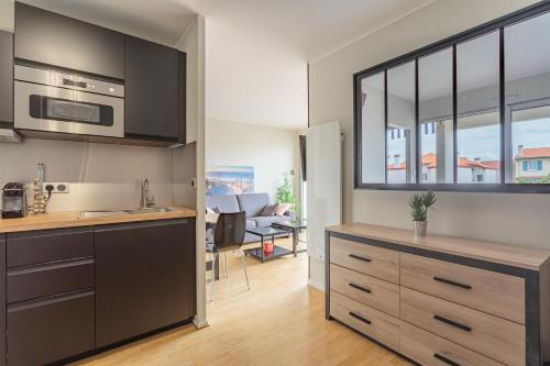 une cuisine avec des armoires noires et un salon dans l'établissement Reine de Serbie, à Biarritz