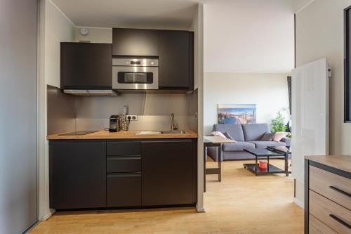 une cuisine avec des armoires noires et un salon dans l'établissement Reine de Serbie, à Biarritz