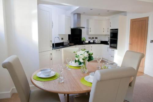uma cozinha com uma mesa de madeira com pratos e flores em Beautiful 3 bedroom house, central Harrogate em Harrogate