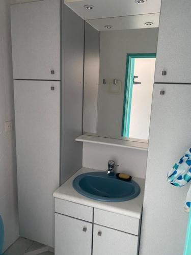 une salle de bain avec un lavabo bleu et un miroir dans l'établissement T2 Vue mer Canet plage, à Canet