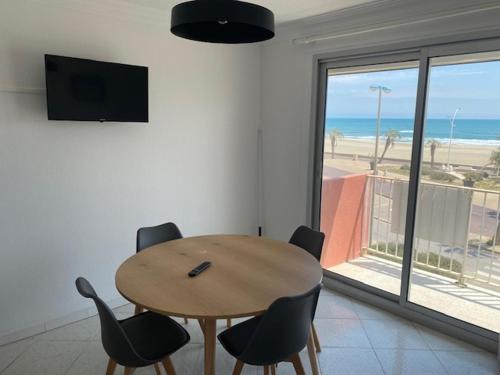 - une table et des chaises dans une chambre avec vue sur la plage dans l'établissement T2 Vue mer Canet plage, à Canet
