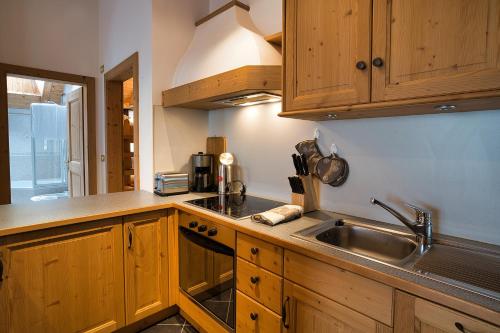 a kitchen with wooden cabinets and a sink at Hotel Monte44 in Selva di Val Gardena