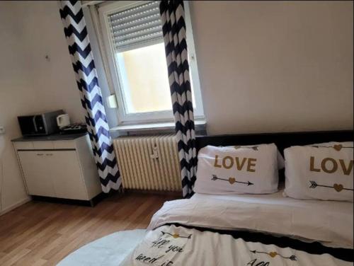 Un dormitorio con una cama con almohadas de amor y una ventana en Wohnung im Zentrum von Darmstadt, en Darmstadt