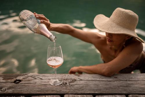 a woman in a hat pouring a glass of wine at Leuchtenburg am See in Caldaro